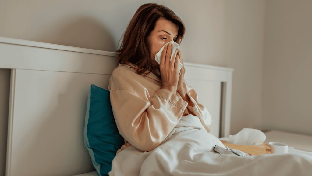 mujer resfriada sonandose los mocos en la cama